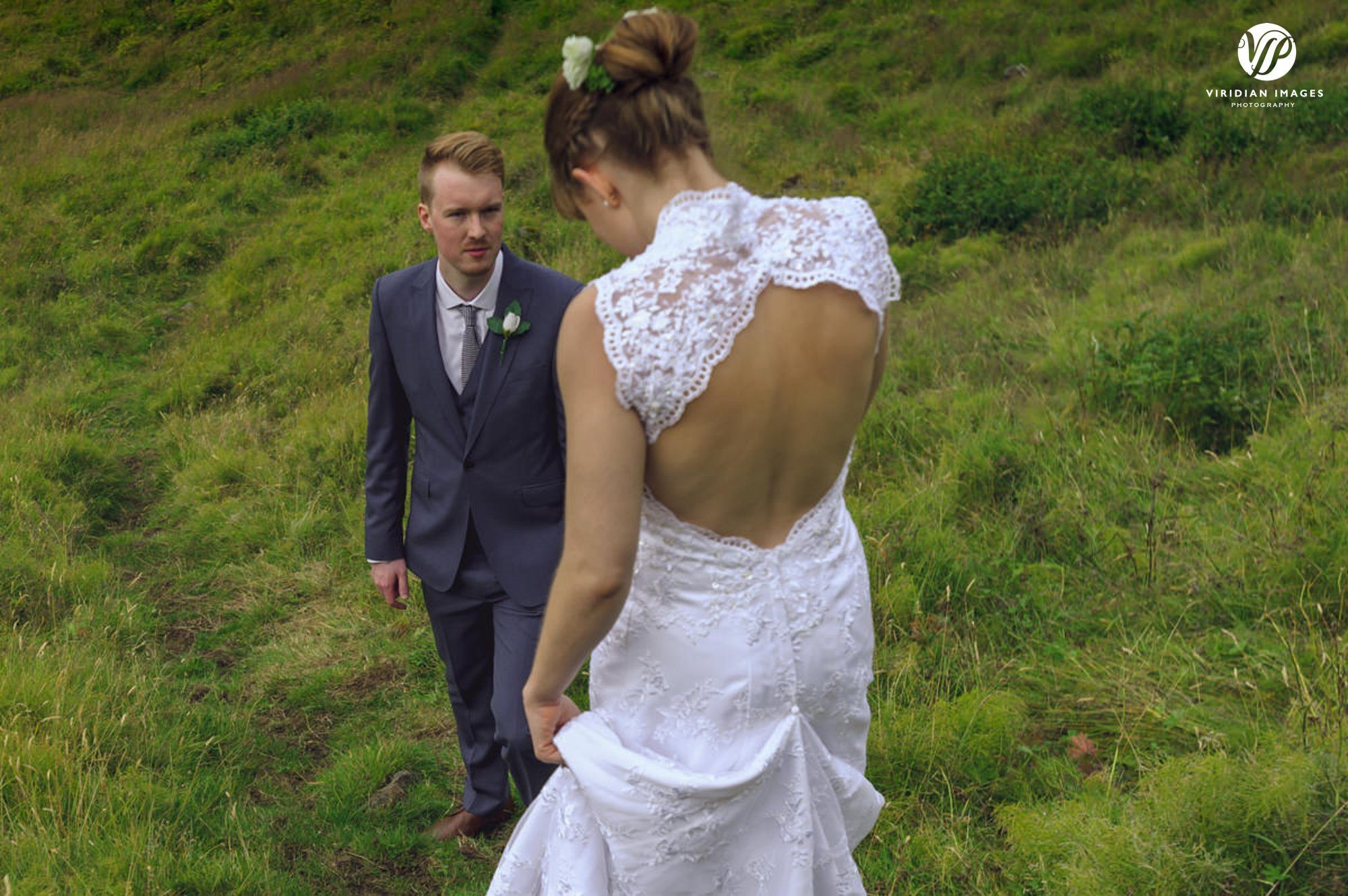 Groom looks emotionally as he helps his new bride down the mountain in Iceland