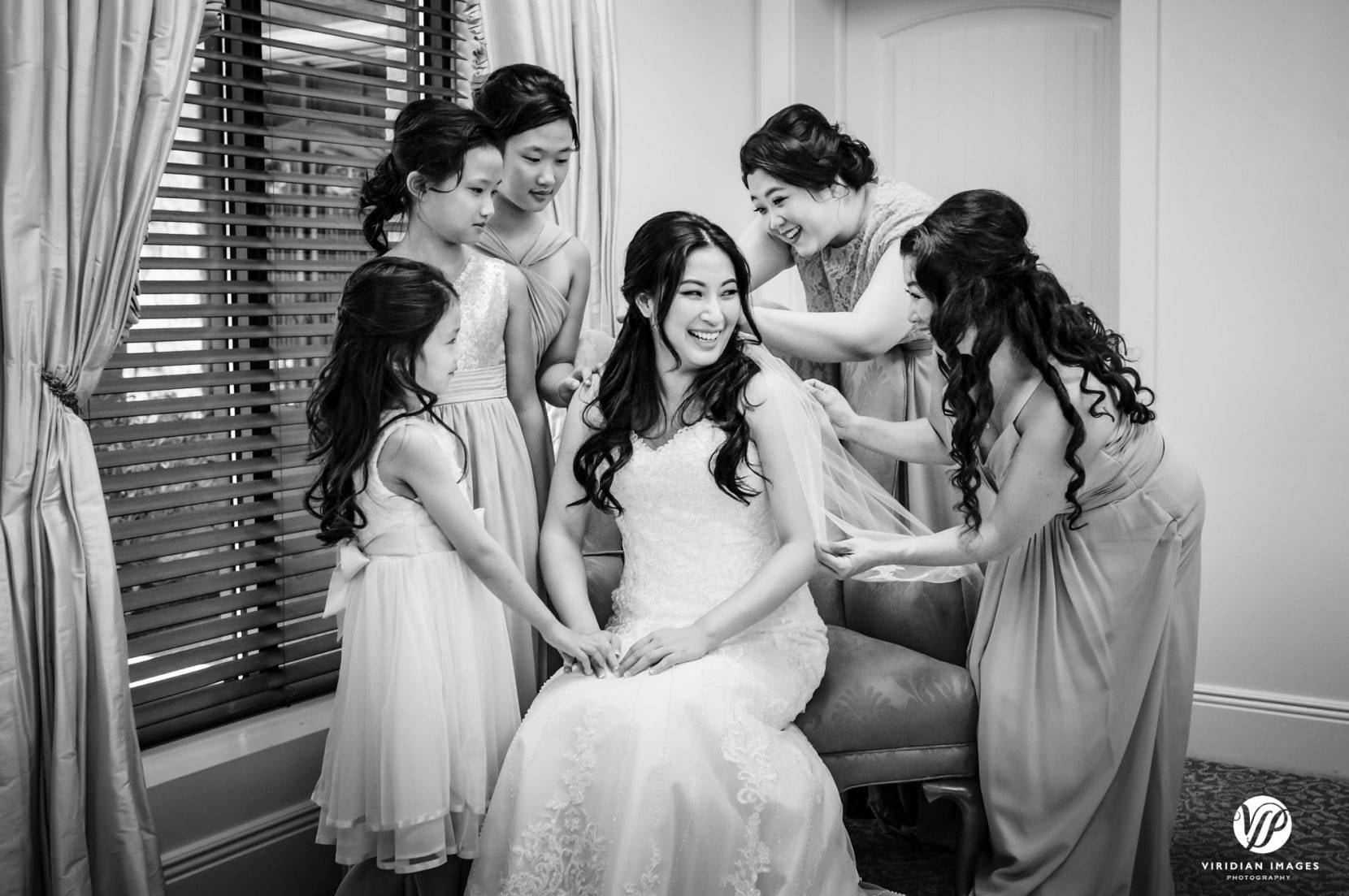 bridesmaids surround bride with dress
