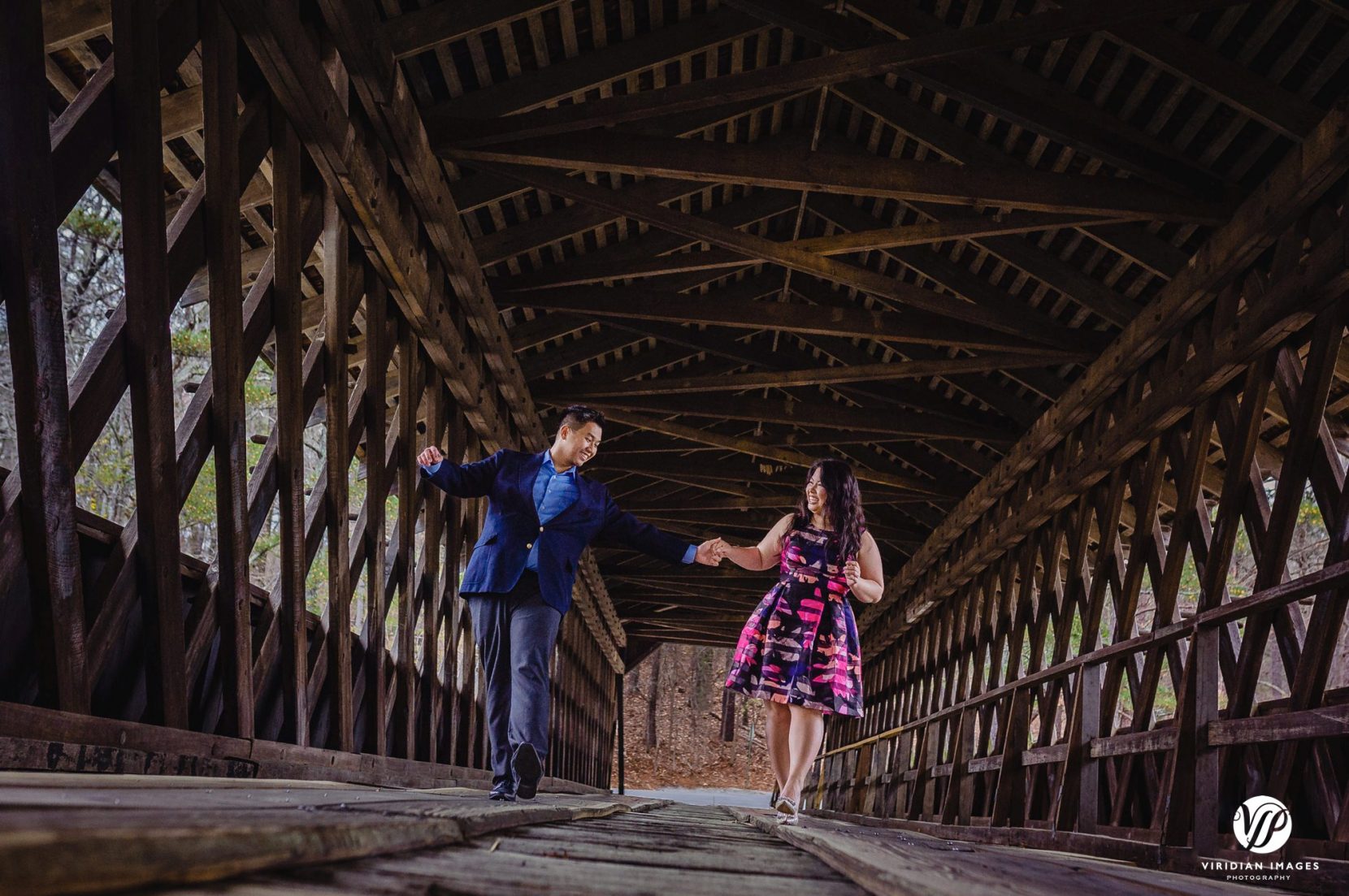 couple playful keeping balance covered bridge in atlanta stone mountain park engagement photo