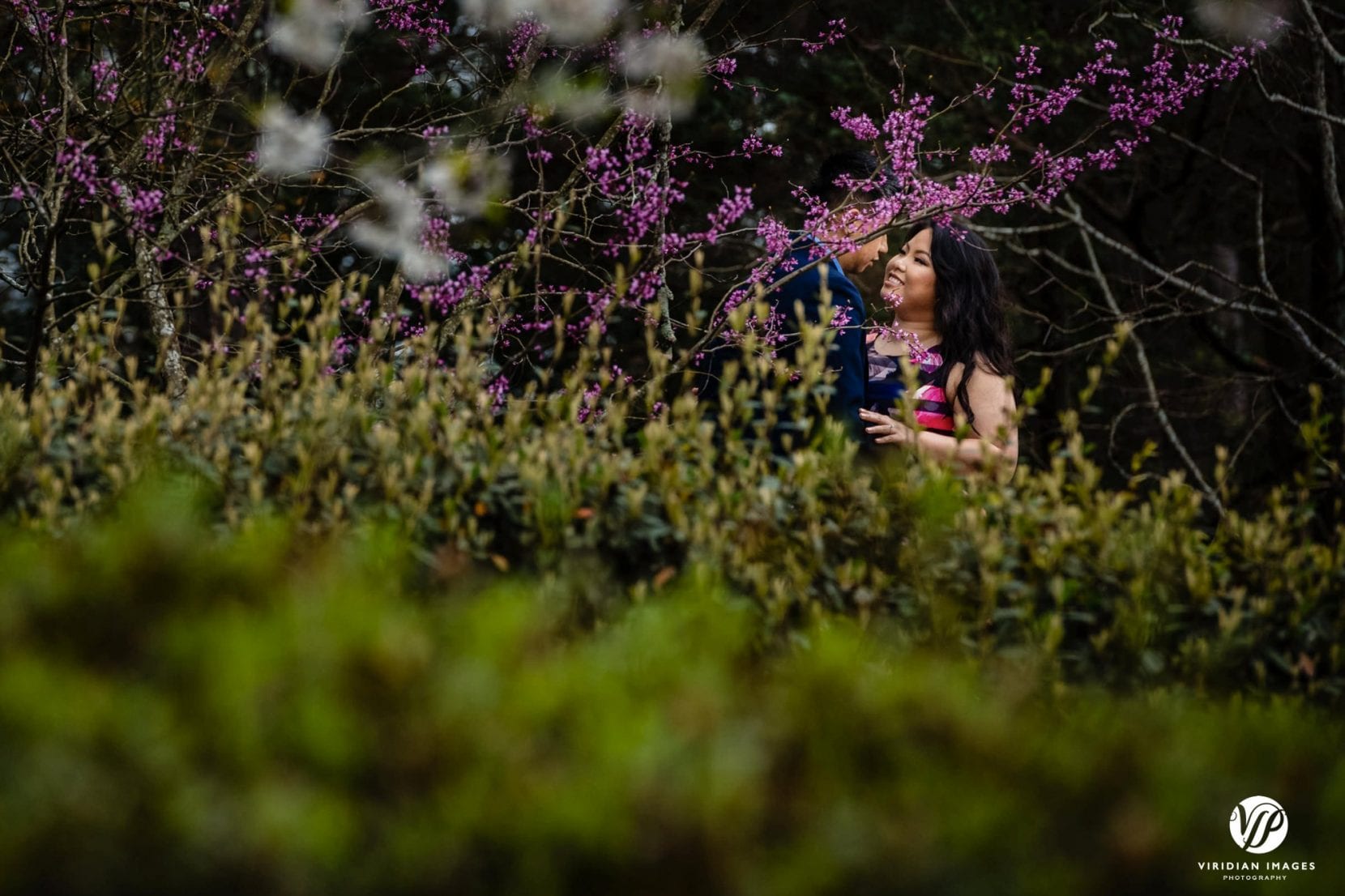 couple smiling flowering trees in stone mountain park atlanta engagement photo