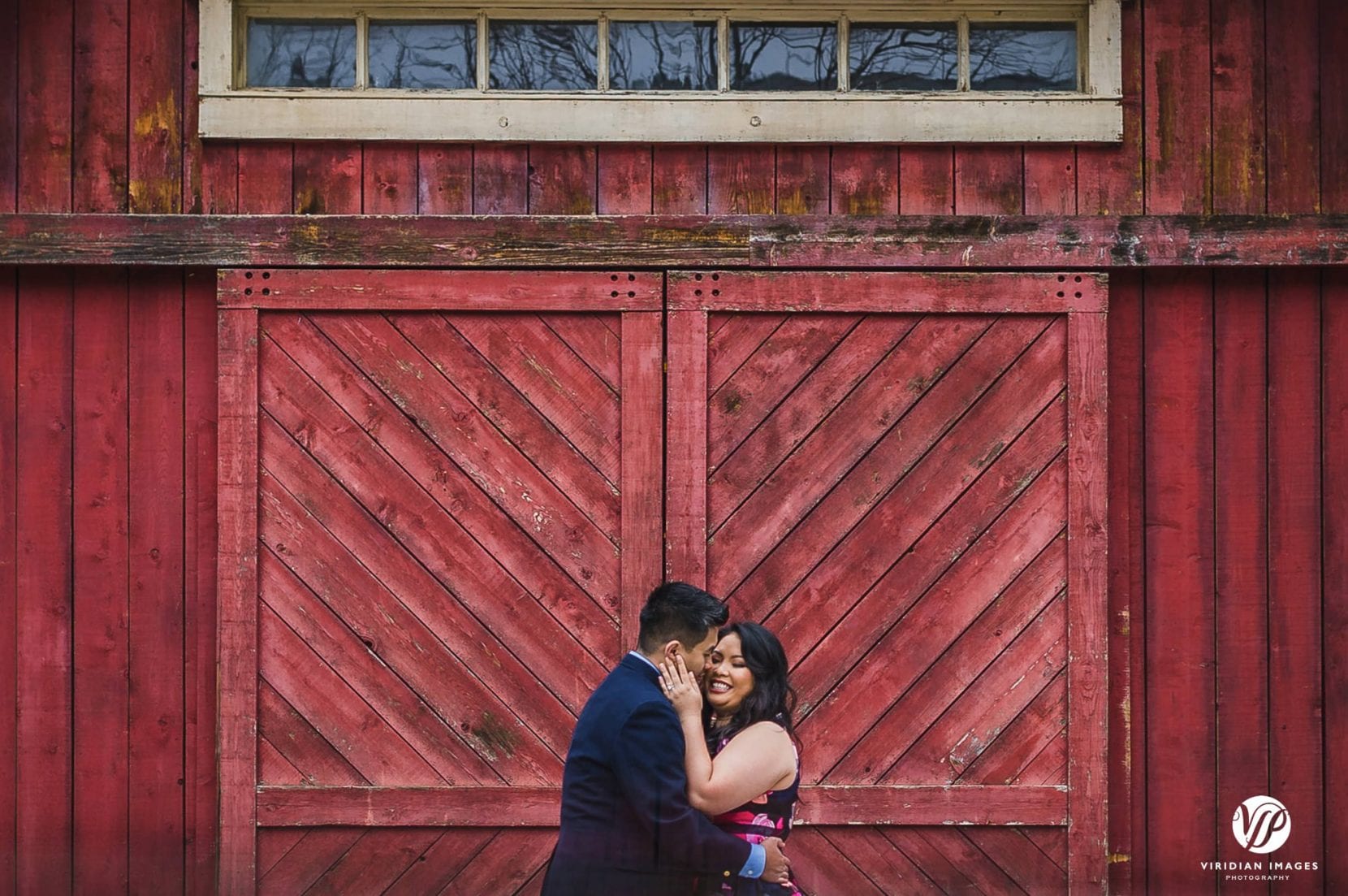 couple romantic hugging front of red barn door in stone mountain park engagement photo