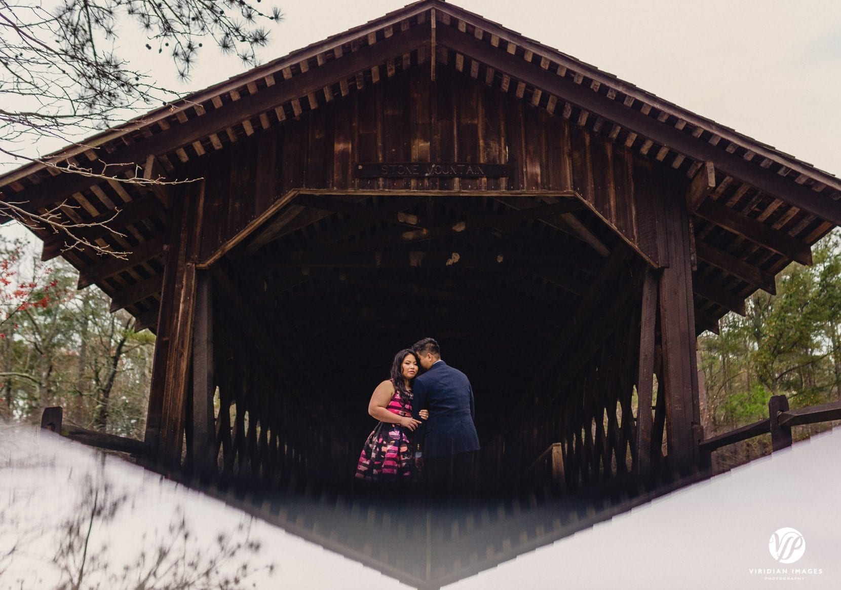 couple reflection covered bridge in stone mountain park atlanta engagement photo