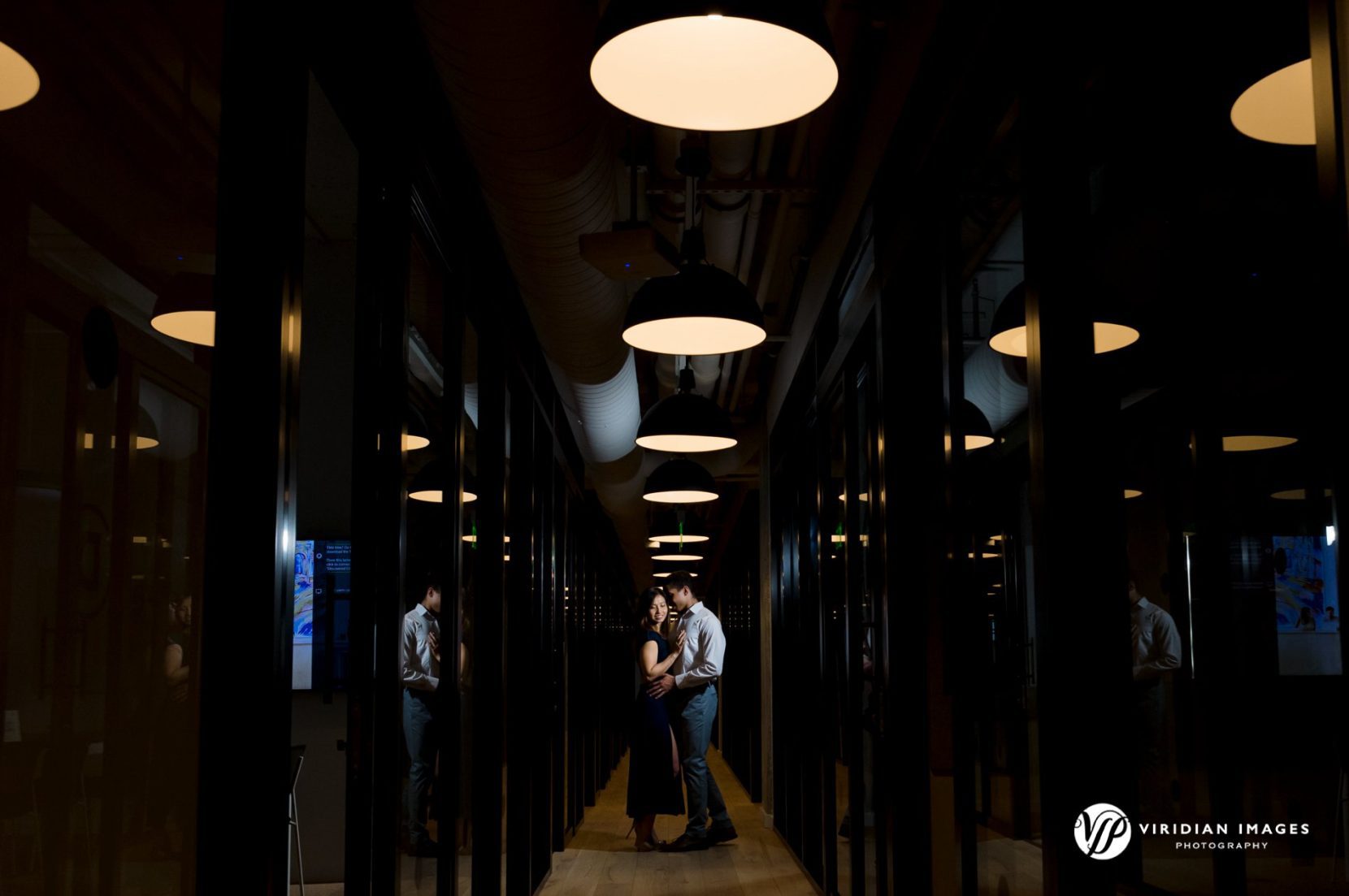 Engaged couple stand in hallway under circular lights at Georgia Tech
