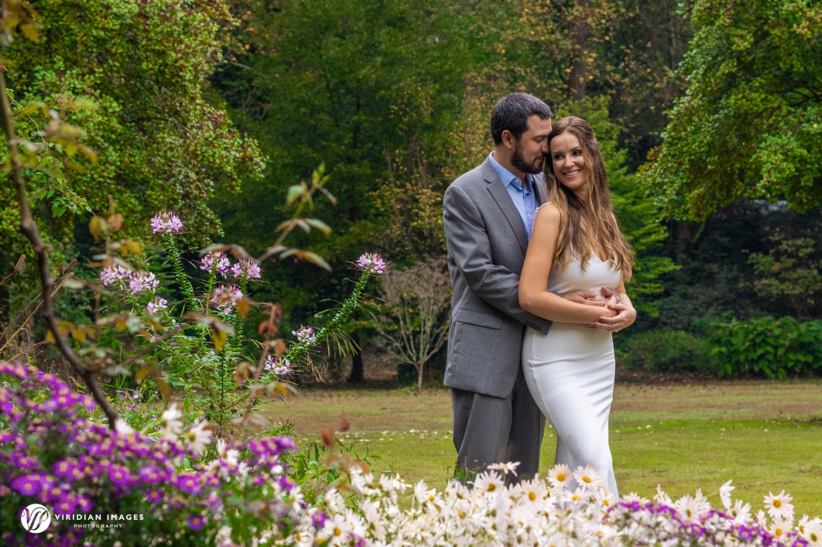 romantic couple hugging with flowers in foreground during engagement session