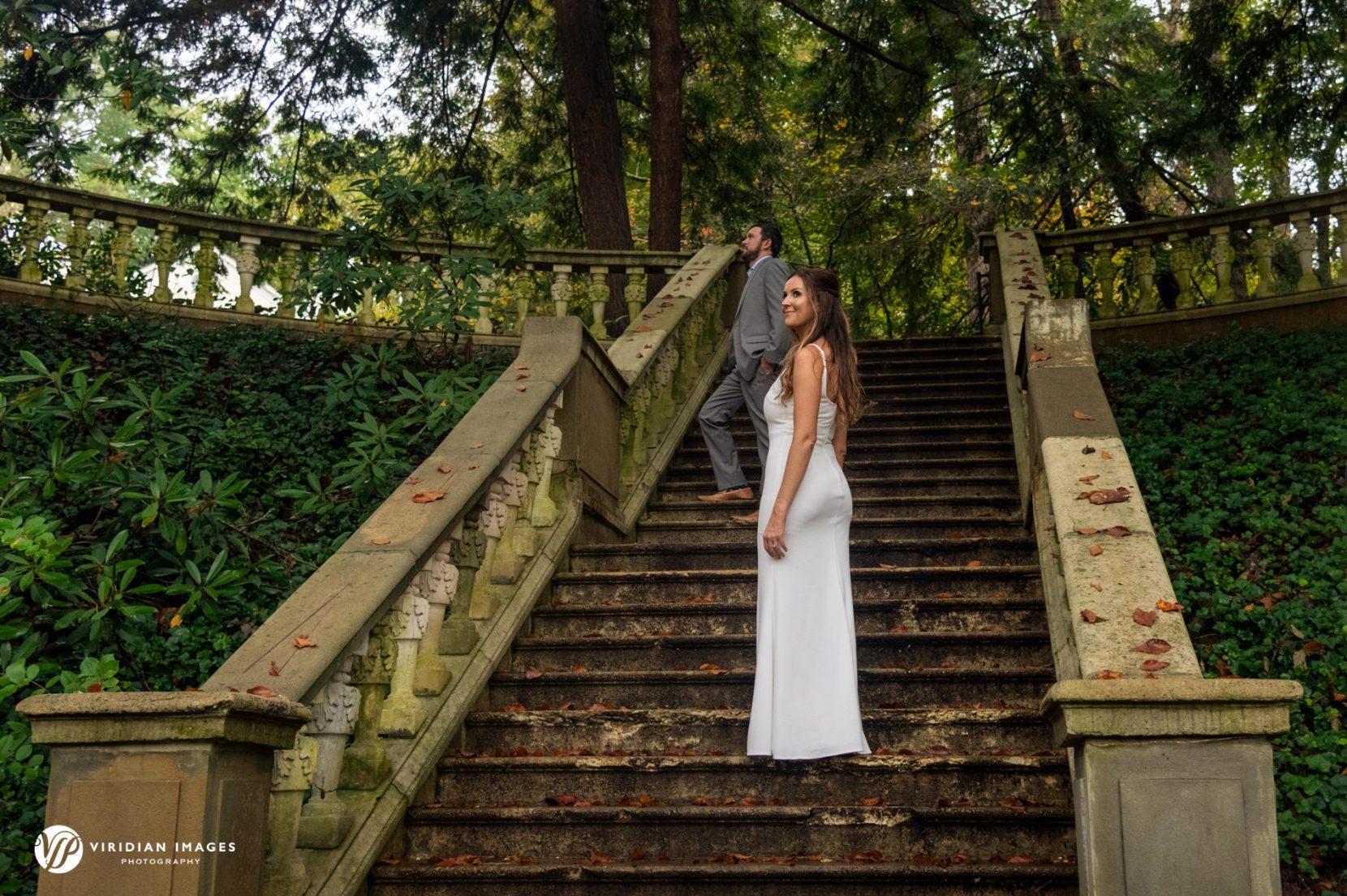 wide shot of couple posed on stone staircase among green foliage in Atlanta