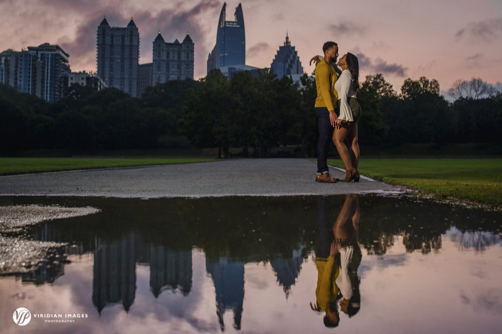 romantic moment of engaged couple with city skyline reflected on puddle in atlanta