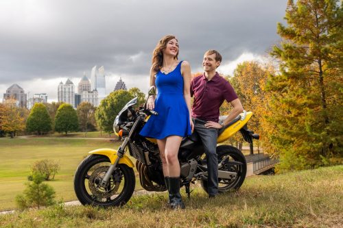 Creative low-angle portrait of Jenny and James with their motorcycles against cloudy fall skies