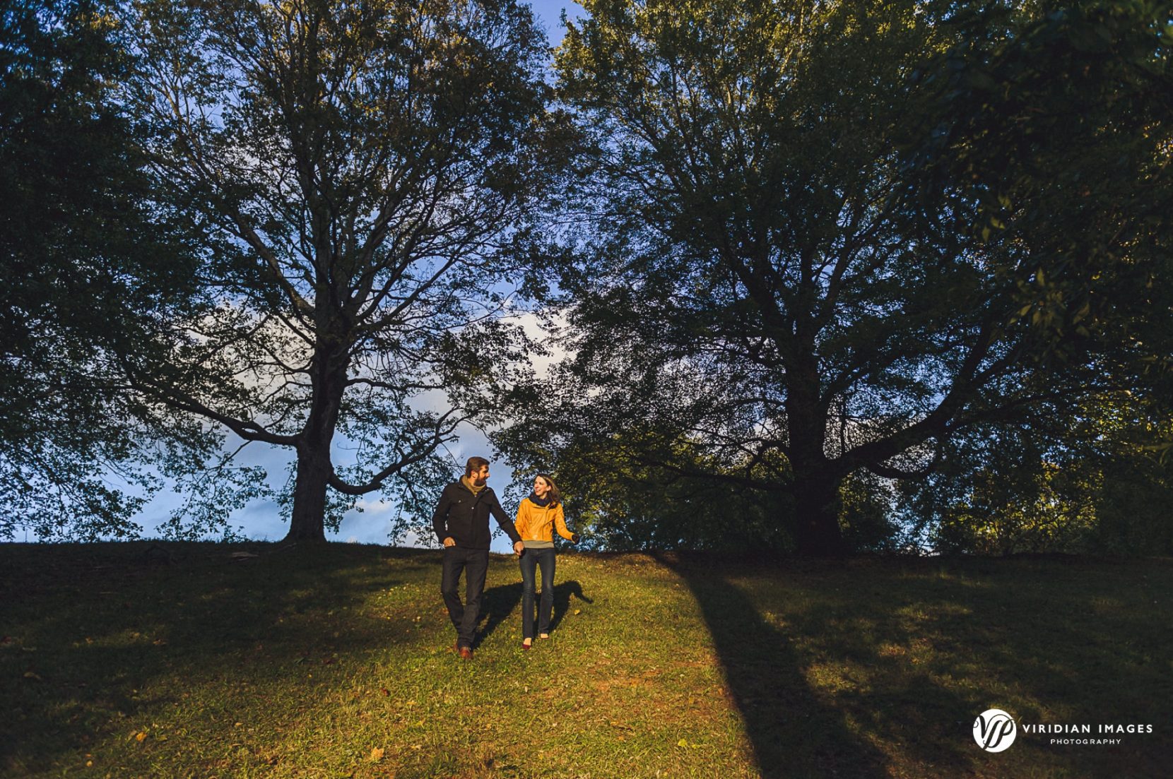 Creative hilltop walking photo of couple coming down hill at sunset in Grant Park.