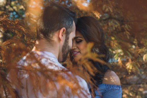 Romantic engaged couple between fall leaves at Piedmont Park