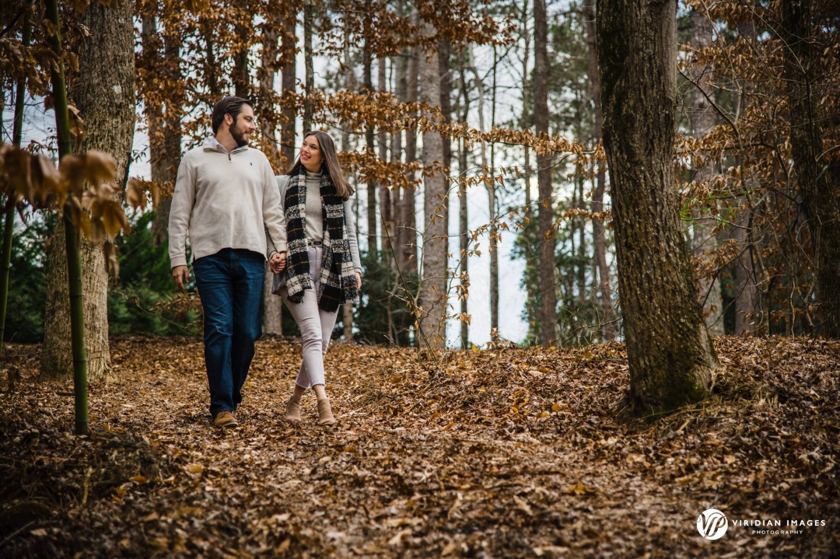 Candid moment of Kelly and Kyle walking down hill during their winter engagement session at Rocky Lake Estate.
