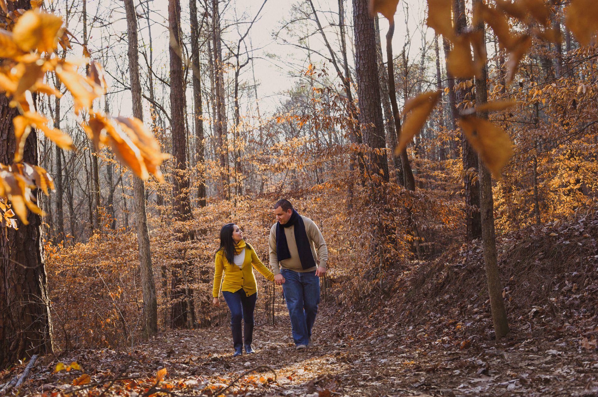 Couple walking together through bare tree trail during their winter engagement session at Sope Creek Trail